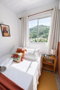 a bed in a room with a large window at Pousada Surf na Guarda in Guarda do Embaú