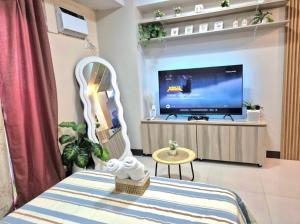 a living room with a tv and a white chair at STUDIO TYPE CEBU CITy in Cebu City