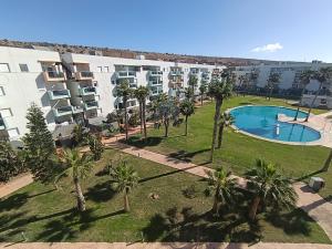 an apartment complex with a swimming pool and palm trees at ALMERIMAR GOLF AND PoOL APARTMENT in Almerimar