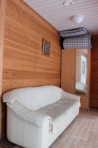 a white couch in a room with a wooden wall at Scandinavian Dream Cottages Vikajarvi- Rovaniemi in Vikajärvi