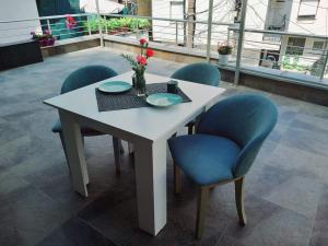 a white table with blue chairs and a vase of flowers at Sokak in Struga