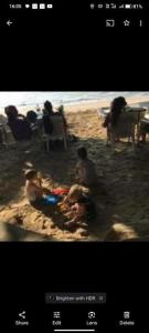 a group of people sitting in the sand at the beach at Blue Moon Villa in Waskaduwa