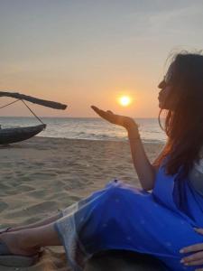 a woman sitting on the beach watching the sunset at Blue Moon Villa in Waskaduwa