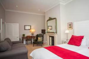 a bedroom with a bed and a couch and a mirror at Blenheim House - Luxury City Centre Georgian Townhouse for 8 in Bath