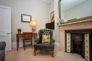 a living room with a chair and a fireplace at Blenheim House - Luxury City Centre Georgian Townhouse for 8 in Bath +14 photos