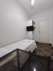a white room with a bed and a television at Hotel Mirian in Patos de Minas