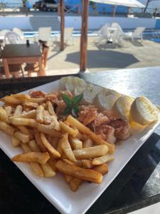 a plate of food with french fries and lemon slices at Pousada Encantos do Mar in Barra de Camaratuba