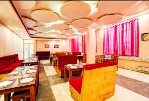 a restaurant with wooden tables and red chairs at Hotel Aroma Regency in Meerut