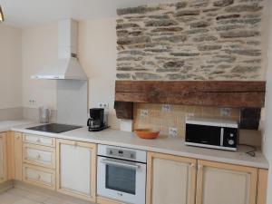 a kitchen with a counter with a microwave and a stone wall at Roz Aon in Châteauneuf-du-Faou