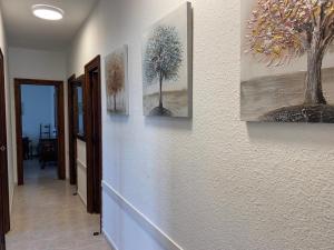 a hallway with three paintings of trees on the wall at Luxuriöses Chalet mit privatem Pool in Roquetas de Mar