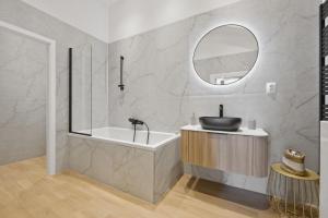 a bathroom with a tub and a sink and a mirror at Primavera - Castle view apartments in Prague +58 photos