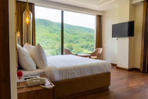 a hotel room with a large bed and a large window at Hotel Malsi Mist in Dehradun