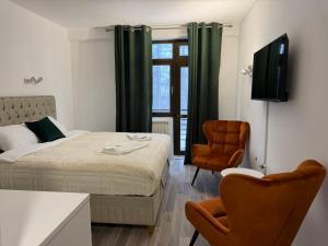 a bedroom with a bed and a tv and a chair at Goldel Resort in Delčevo