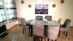 a dining room table with chairs and a painting on the wall at Legacy by Fralec in Nyeri