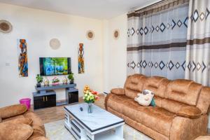 a living room with a couch and a tv at Legacy by Fralec in Nyeri