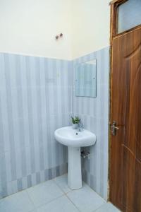a bathroom with a white sink and a wooden door at Legacy by Fralec in Nyeri