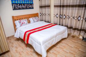 a bedroom with a bed with a red and white blanket at Legacy by Fralec in Nyeri