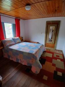 a bedroom with a bed and a wooden ceiling at Casa Amarela in Bocaina de Minas