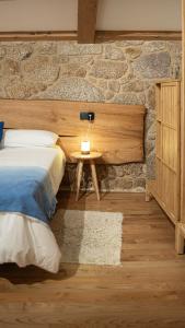 a bedroom with a bed and a stone wall at iSlow Costa da Morte in Laxe