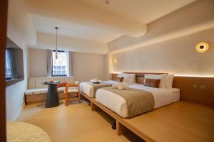ein Hotelzimmer mit zwei Betten und einem Tisch in der Unterkunft Marwin Terra Hotel in Bangkok