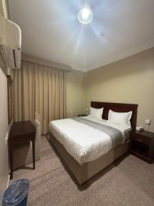 a bedroom with a large bed with white sheets at سحابة صيف للشقق المخدومه 1 - حي النزهه - in Abha
