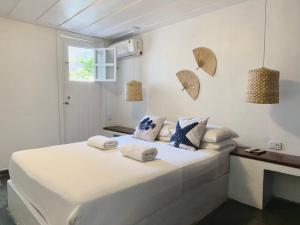 a white bedroom with a bed with towels on it at Peixe Crew Centro in Búzios +72 photos