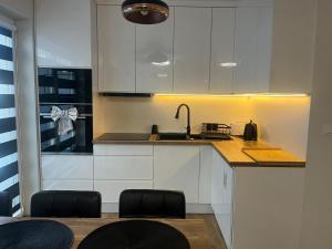 a kitchen with white cabinets and a sink at Apartament w Centrum z wanną z hydromasażem in Kętrzyn