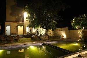 a swimming pool in front of a house at night at Nesara the nature villa in Jāmb