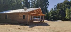 a small wooden building with a metal roof at Cabaña con rio y camping in Los Ángeles