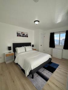 a white bedroom with a large bed and a window at Cozy blue house in Salt Lake City