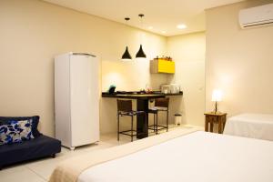 a room with a bed and a kitchen with a refrigerator at Flats Premium Jabaquara in Paraty