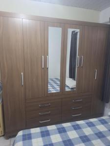 a bedroom with a wooden cabinet with a mirror at Ambiente Familiar in Alagoinhas +3 photos