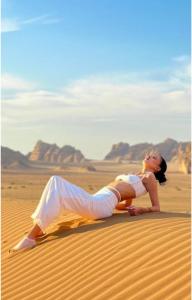 a woman is laying on the sand in the desert at RUM iSLAND bubble LUXURU CAMP in Wadi Rum