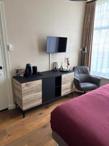 a bedroom with a dresser with a tv and a chair at B&B de Trochset in Balk