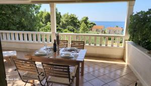 a table and chairs on a balcony with a view of the ocean at Apartmani Dolac in Ivan Dolac