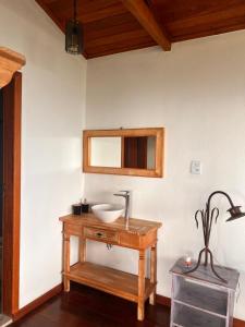 a bathroom with a sink and a mirror on a table at Chalé da Mata Lavras Novas in Lavras Novas