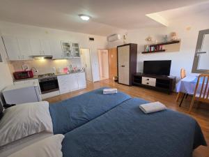 a bedroom with a blue bed and a kitchen at Tonino Apartment in Pag