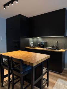 a kitchen with a wooden table and black cabinets at Apartament City Rent Płock in Płock