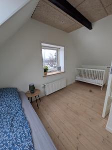 a bedroom with a bed and a window and a wooden floor at Hus 5 personer in Hjørring
