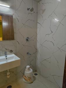 a white bathroom with a sink and a mirror at Hotel Cozzy Inn in Bangalore