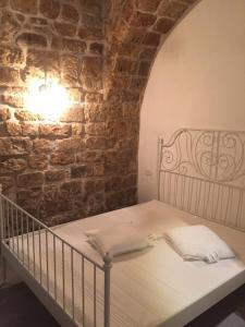 a bed in a room with a brick wall at Acre Two Wells Zimmer in ‘Akko