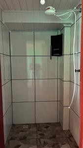 a shower with a glass door with a television in it at Pousada Azambuja in Cidreira