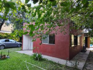 a red house with a car parked in the yard at CASA QUINTA Sasha in Sauce Viejo