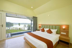 a bedroom with a large bed and a large window at Lanka Valley Resorts in Sāsthānkotta +43 photos