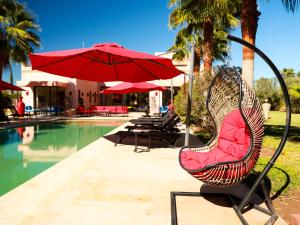 a chair with a red umbrella next to a pool at Villa des iris Domaines NAJMA in Marrakesh