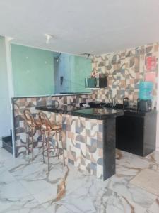 a kitchen with a counter and two chairs in a room at Pousada Terraço do Peró Cabo Frio Há 200 metros da Praia in Cabo Frio