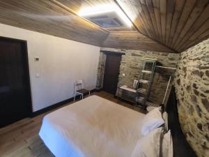 a bedroom with a large bed and a stone wall at Casa do Porco - Farm Stay & Spa no Douro in Melres