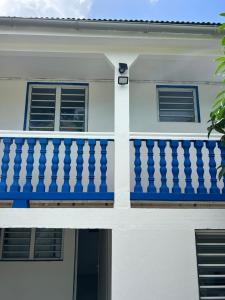 a white house with a blue balcony at Dolce Vita Emilia in Sainte-Luce