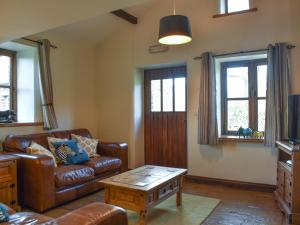 a living room with a leather couch and a coffee table at Oaktree Cottage-Uk42227 in Low Borrowbridge