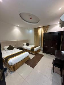 a hotel room with two beds and a desk at جميــرا لاين in Abha
